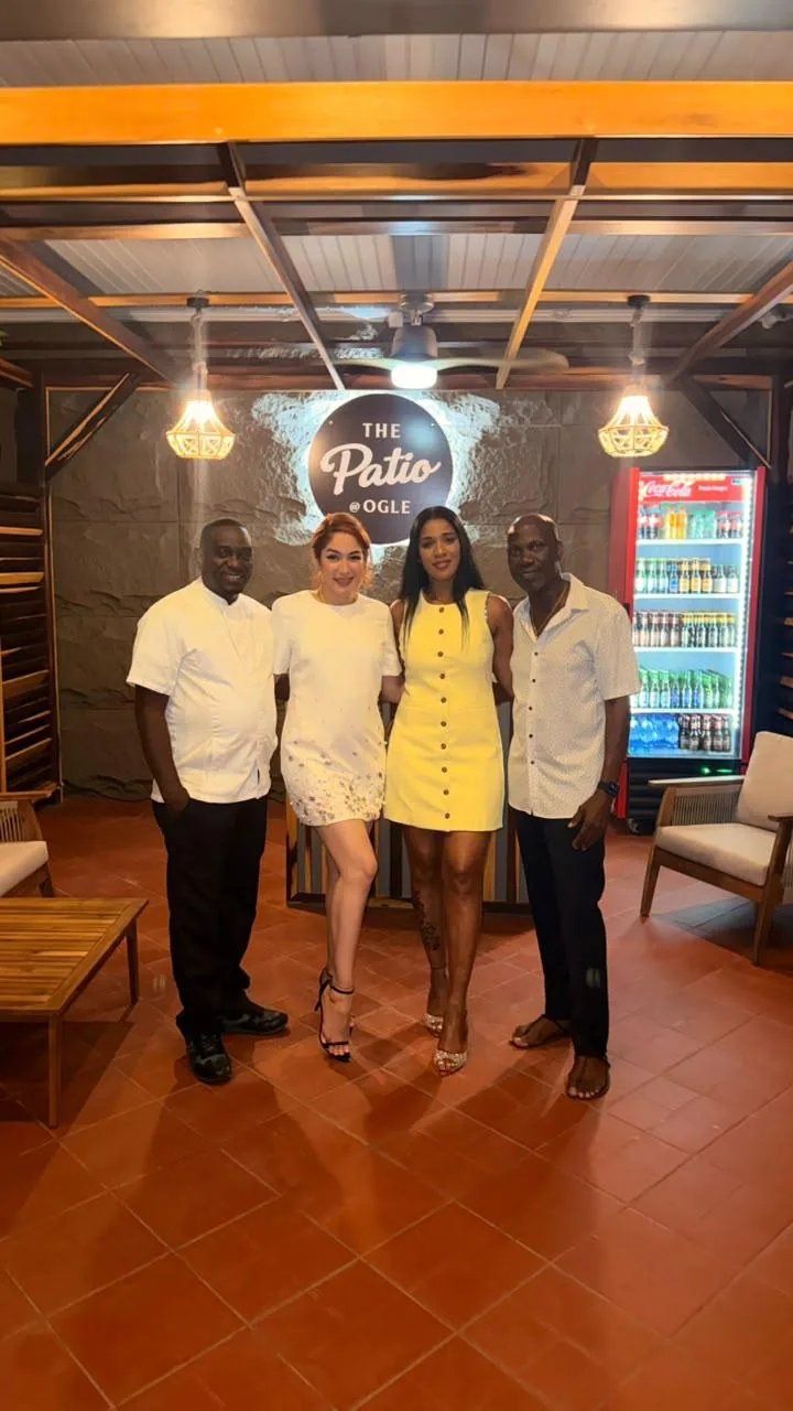 Four people posing beneath The Patio sign